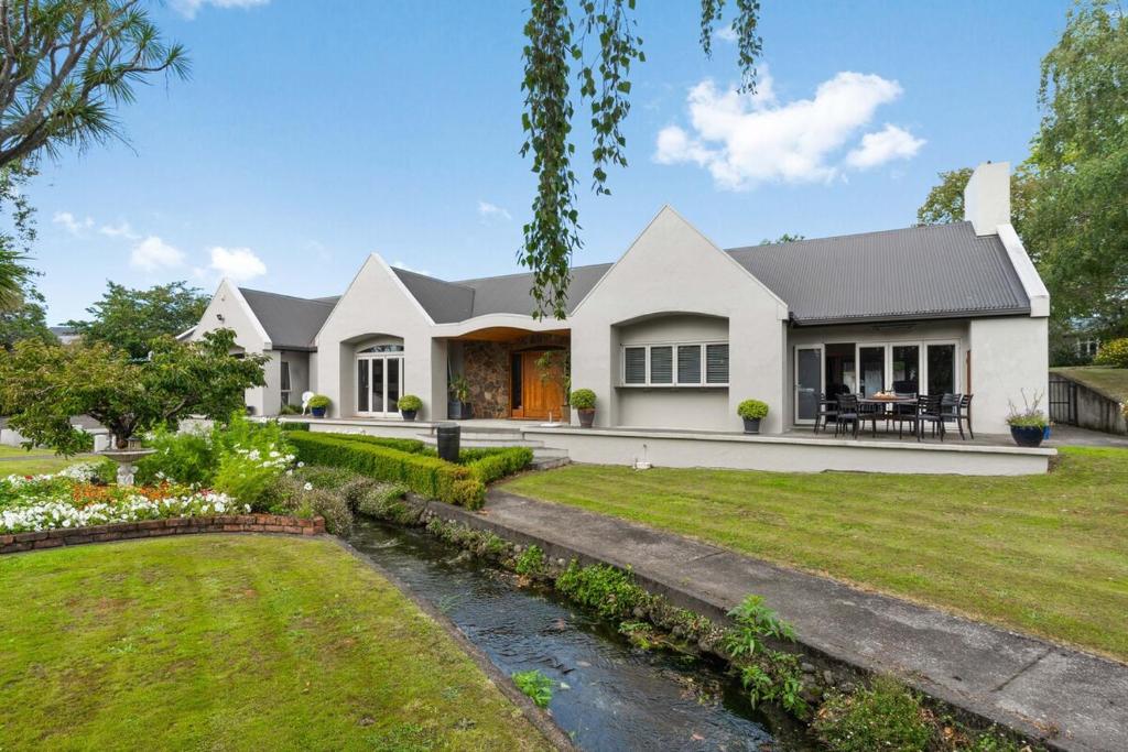 a white house with a stream in front of it at Renall St Gem Central Masterton in Masterton