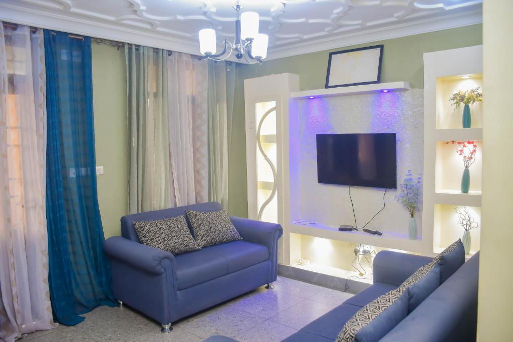 a living room with a blue couch and a tv at Appart Naxel in Kinshasa