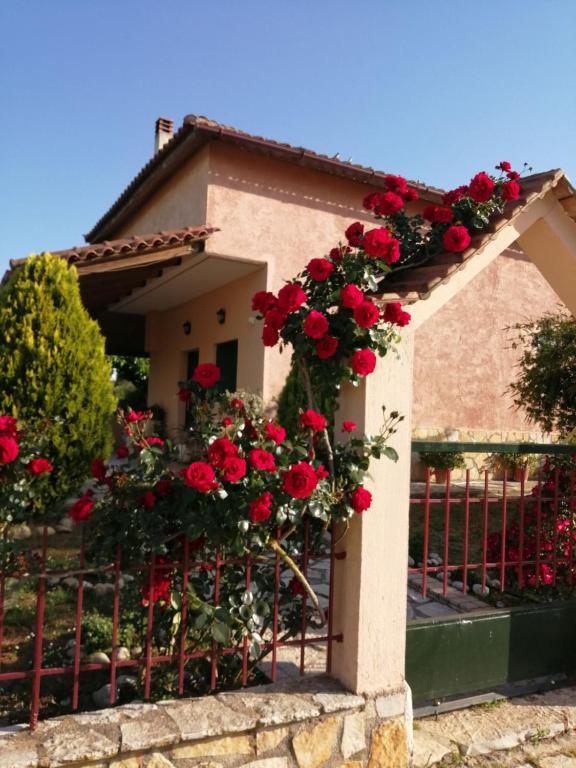a house with red roses on a fence at Monica's Country House in Nafplio