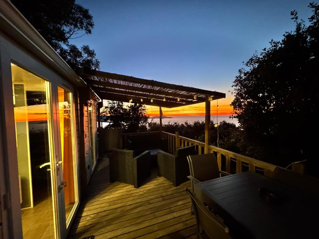a deck with chairs and a pergola at sunset at U paradisu in Lumio