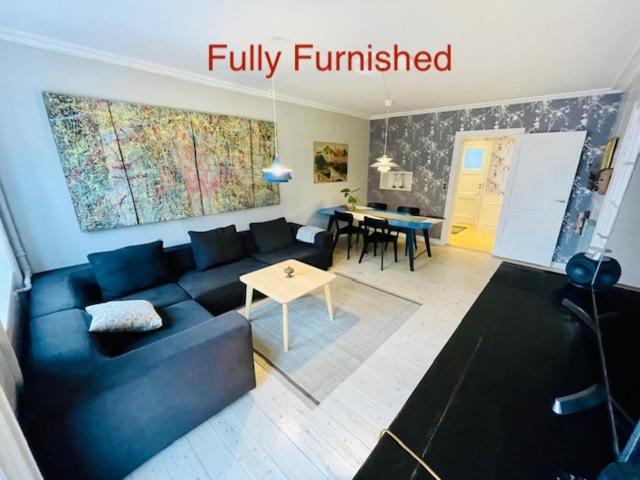 a living room with a blue couch and a table at Deluxe Hotel Apartment in Charlottenlund
