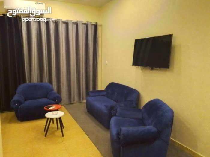 a living room with two blue chairs and a tv at Larain Plaza Hotel in Aqaba