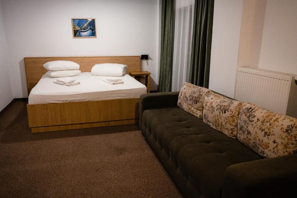 a hotel room with a bed and a couch at Casa Lazaroiu in Curtea de Argeş