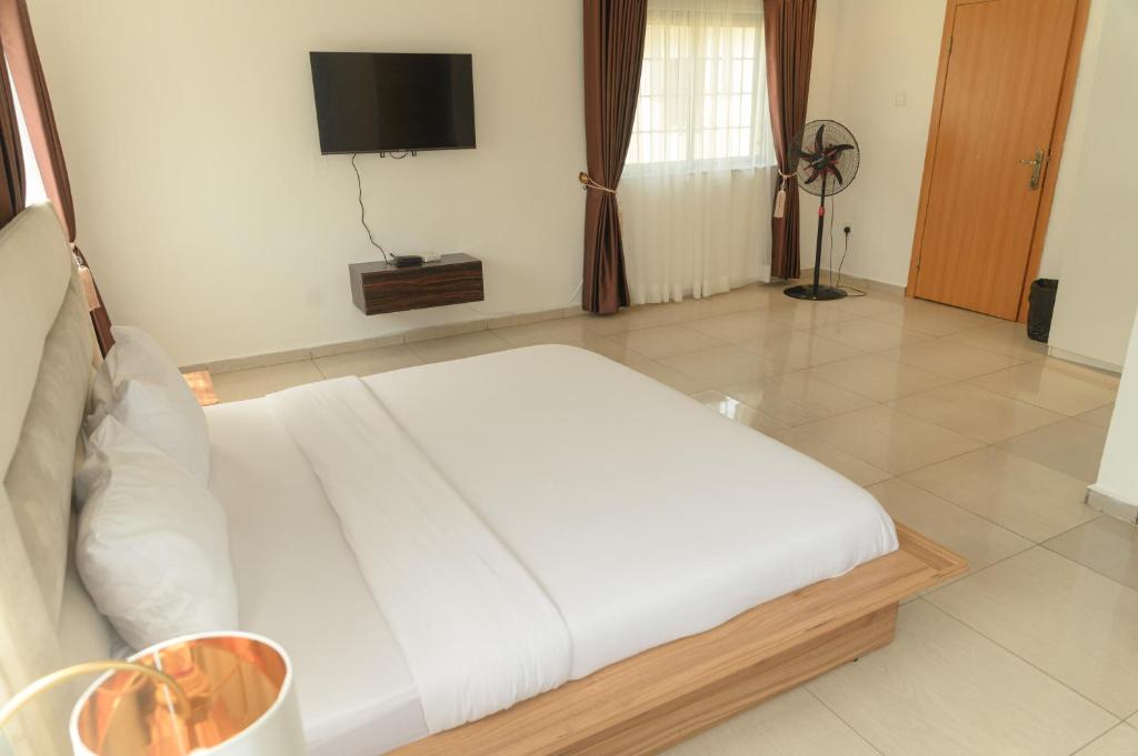 a bedroom with a white bed and a flat screen tv at The Lekki Retreat in Lekki
