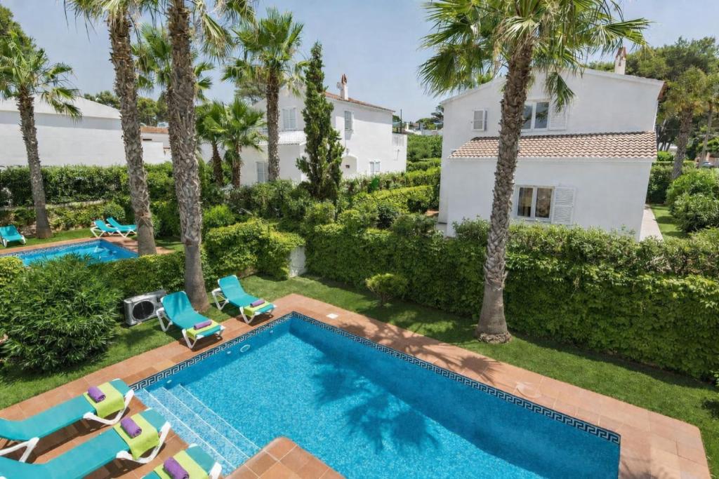 an aerial view of a swimming pool with palm trees and a house at Villas Serena in Cala Blanca