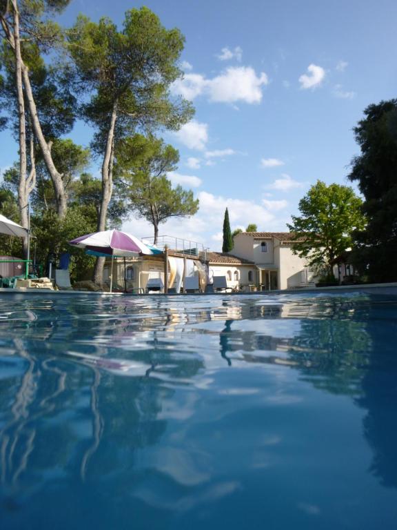 a swimming pool with an umbrella and a house at Lou Mazet - Entre Vignes et Garrigue in Valflaunès