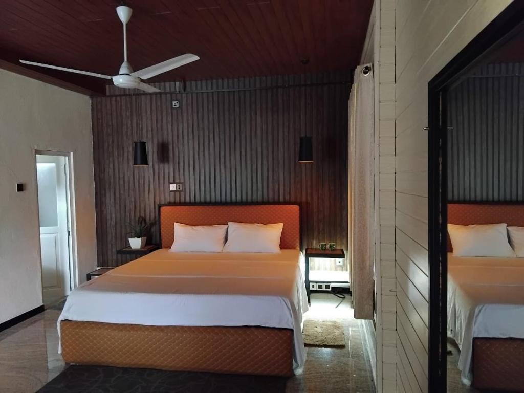 a bedroom with a large bed and a ceiling fan at Forest Garden Cottages in Deraniyagala