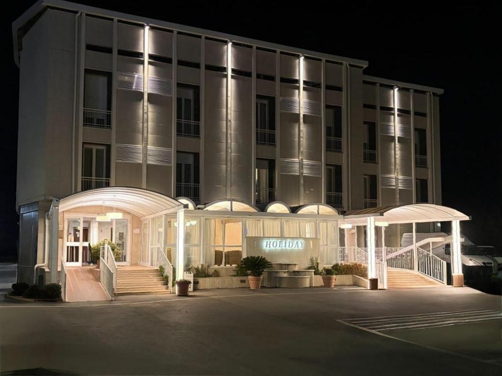 a large building with an entrance to a hotel at night at Hotel Holiday in Foggia