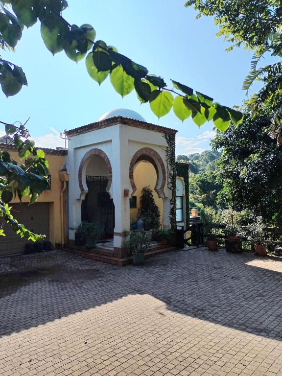 a building with a gate and a brick courtyard at Le Chemin Guesthouse - 6 sleeper in Kloof