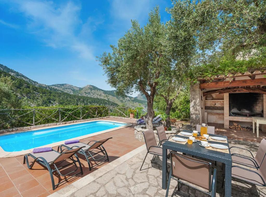 a patio with a table and chairs next to a swimming pool at Villa Es Barracar Caimari in Caimari