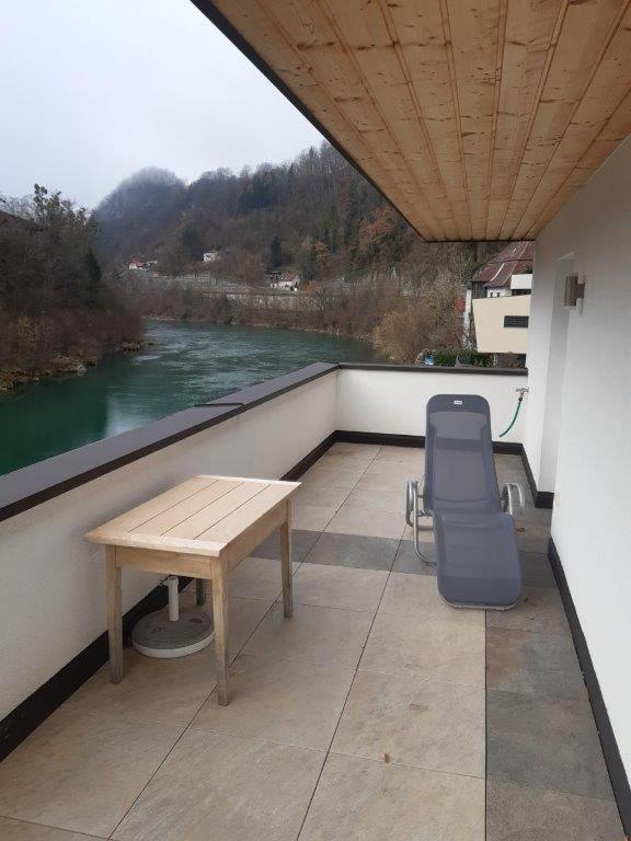 a table and a chair on a balcony with a river at Neue Wohnung am Fluss in Losenstein