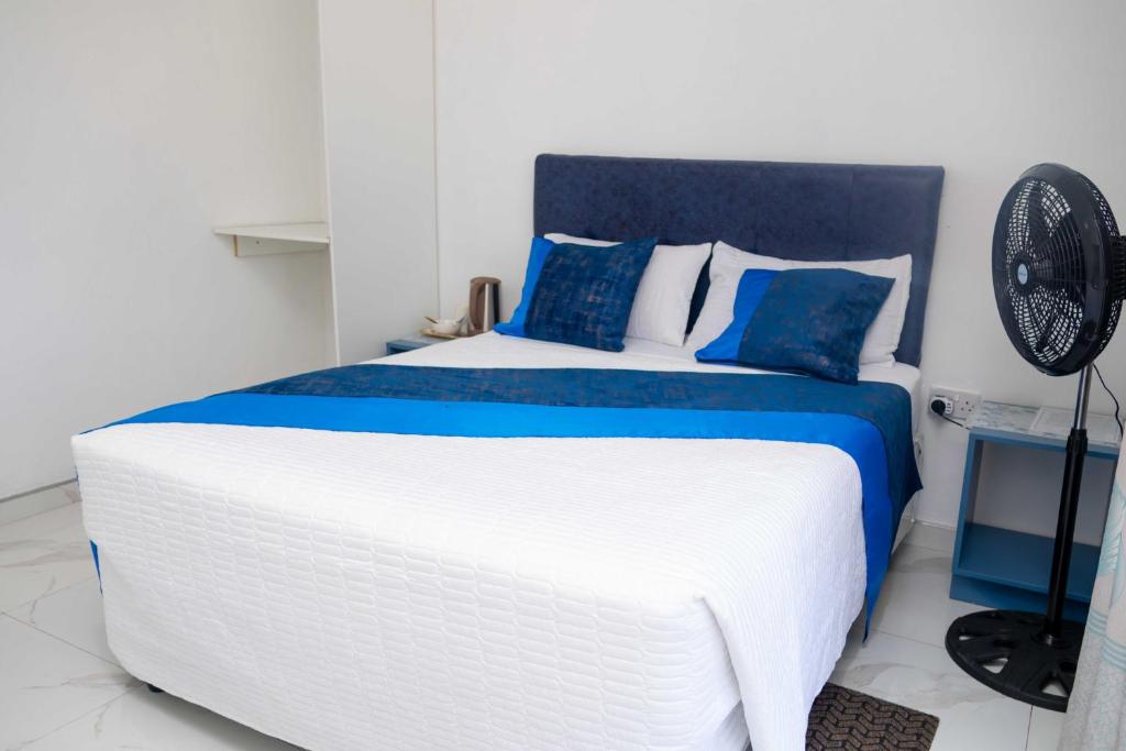 a white and blue bed in a room with a fan at Elclassico Villa in Nyanda