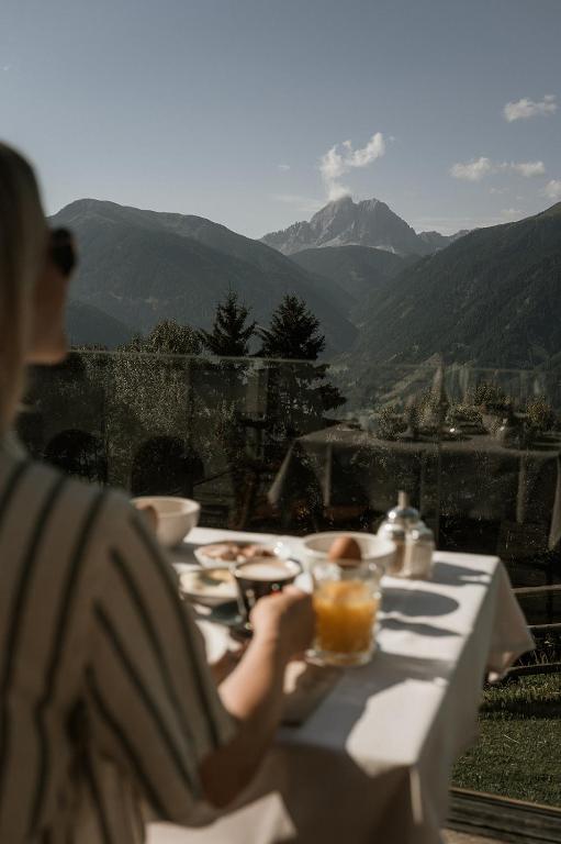 a woman sitting at a table looking out at the mountains at Herol - my mountain retreat in Luson