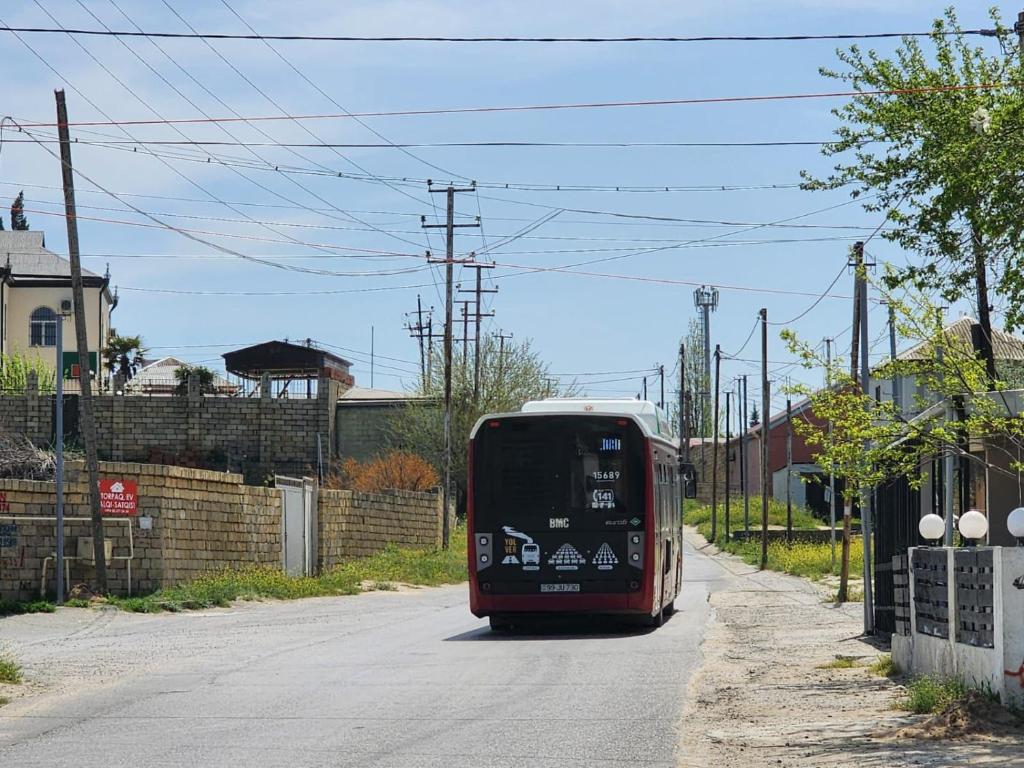 a red bus is driving down a street at Görədil bağ evi in Mekhrably
