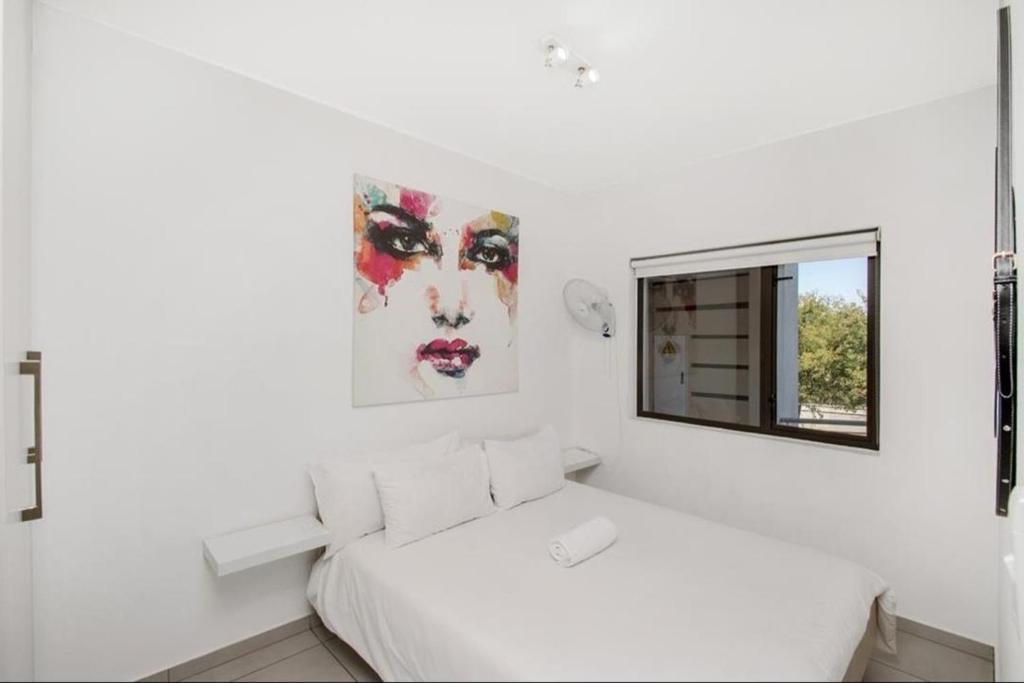 a white bedroom with a bed and a window at Soho Junction fourways in Sandton