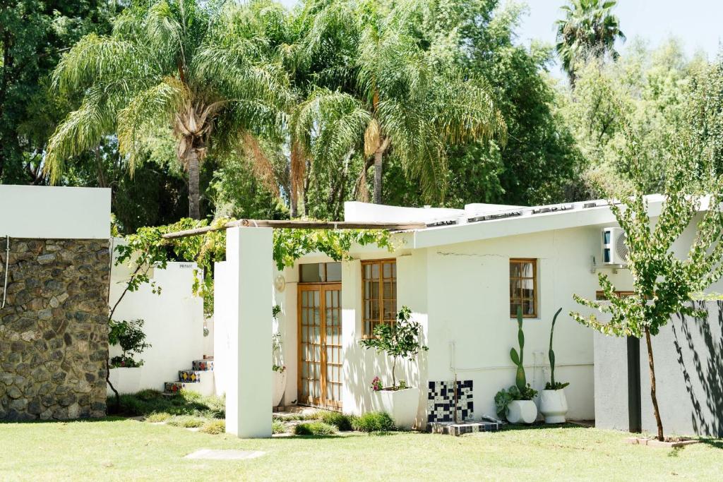 a white house with palm trees in the background at Kanaal kooi in Upington