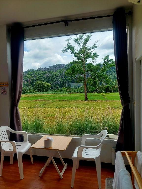 a room with a large window with a table and chairs at เจอาร์รีสอร์ท ที่พักบ้านมุงเนินมะปราง in Ban Mung