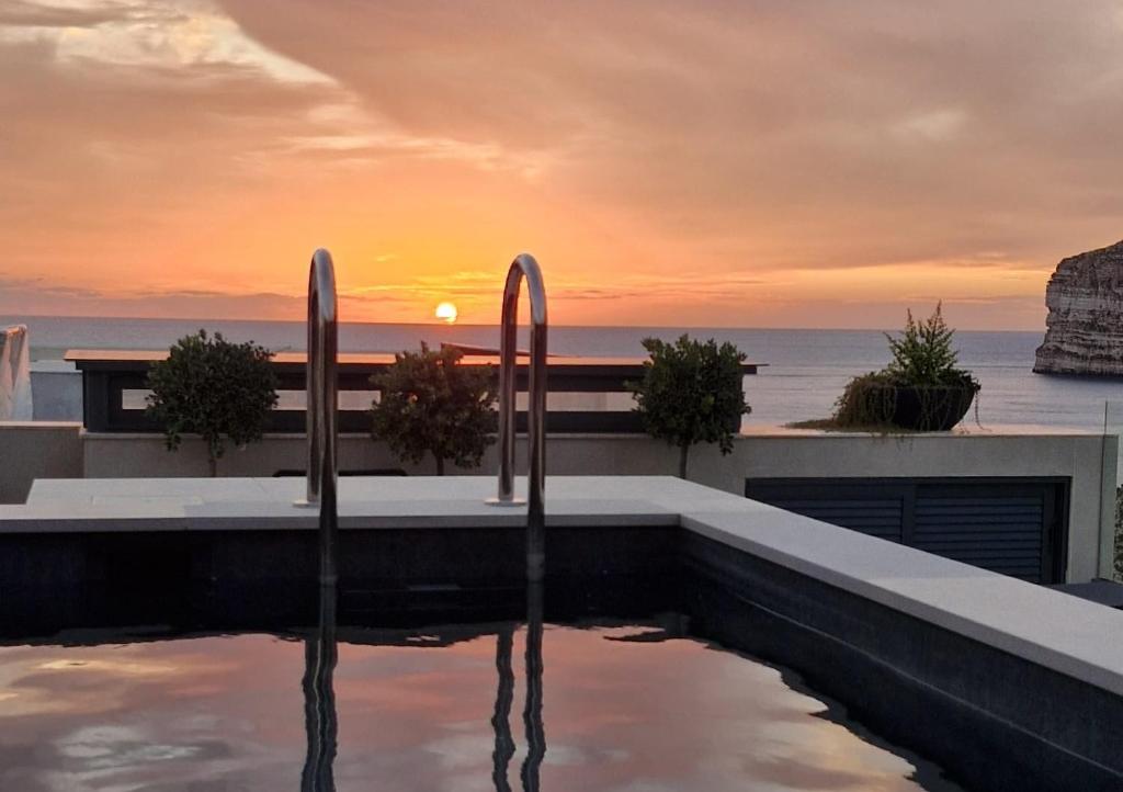 a swimming pool with the sunset in the background at GOZO DIVE Residence in Xlendi