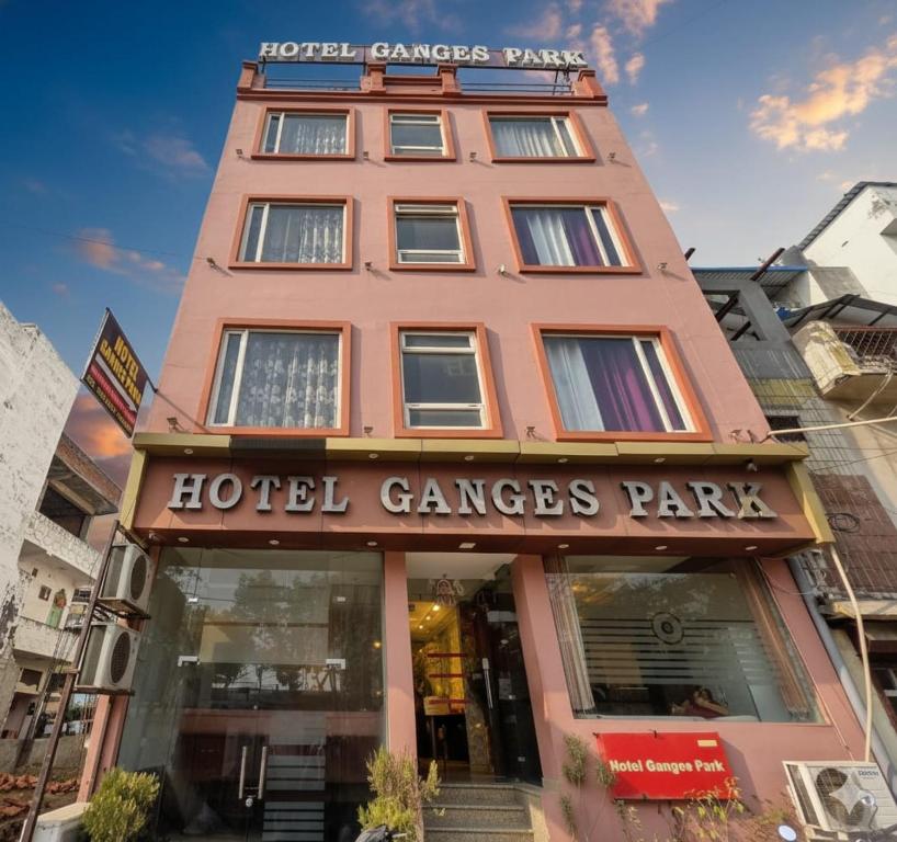 a large pink building with a hotel garage park at Hotel Ganges Park in Haridwār
