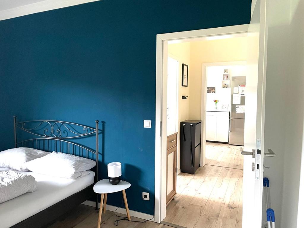 a bedroom with a blue wall and a bed and a stool at City Wohnung in Haltern gratis Parken, Netflix & Wäschepaket in Haltern