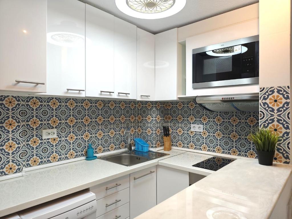a kitchen with white cabinets and a sink and a microwave at 009 Bungalow Torrelamata in La Mata