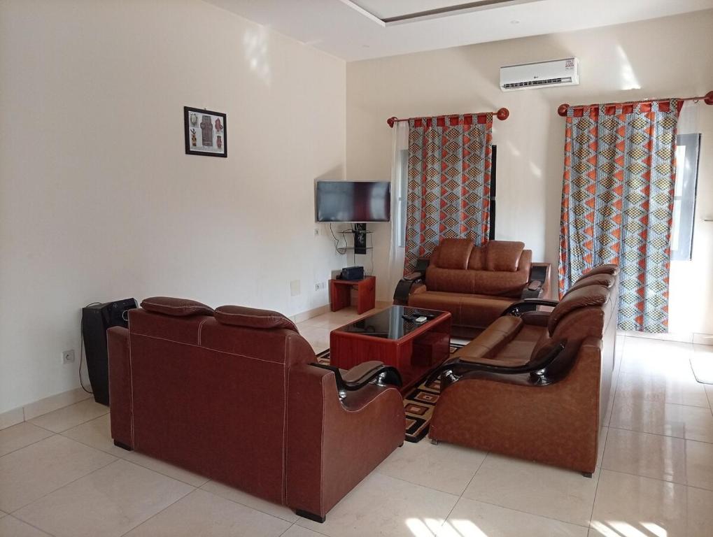a living room with chairs and a couch and a tv at A quiet corner in Cotonou in Cotonou
