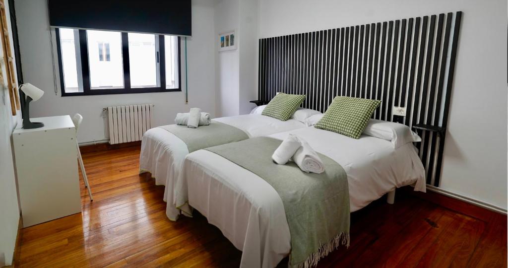 a bedroom with two beds with green pillows at Apartamentos Campus Arzúa in Arzúa