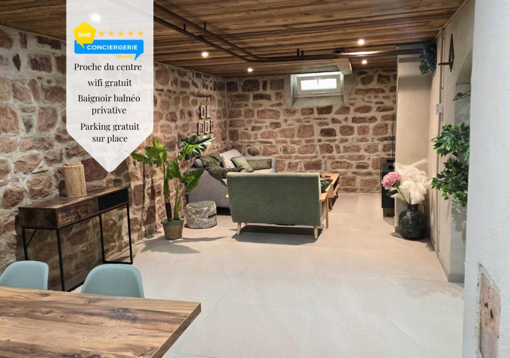 a room with a stone wall and a table and chairs at La Cav'O Bulles - Balnéo privative - parking in Obernai