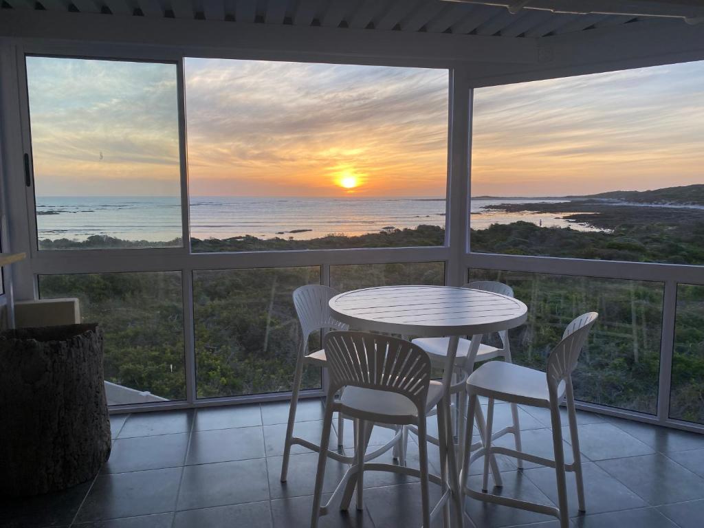 a table and chairs on a balcony with a view of the ocean at Ganstever Suiderstrand Western Cape in Suiderstrand