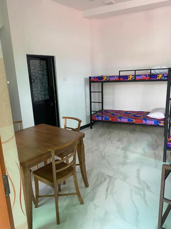 a room with a table and a desk and bunk beds at Chandani Hostel in Galle