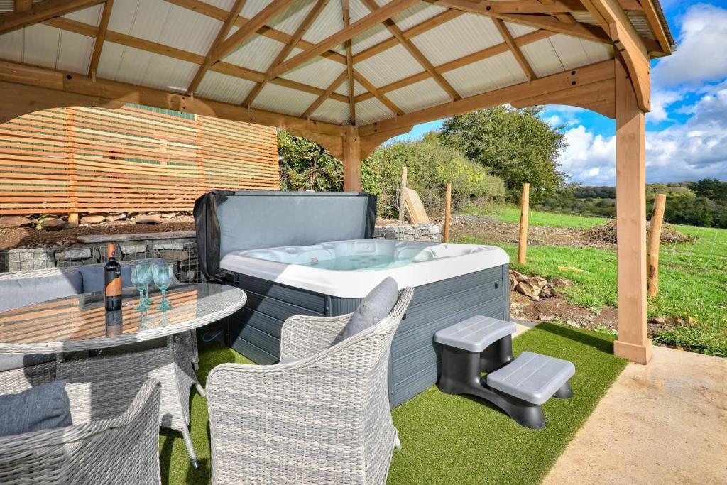 a patio with a hot tub and a table and chairs at 2 Bed in Abererch oc-glwysf in Abererch