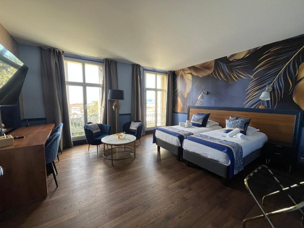 a hotel room with a bed and a table and chairs at Hôtel Windsor in Cannes