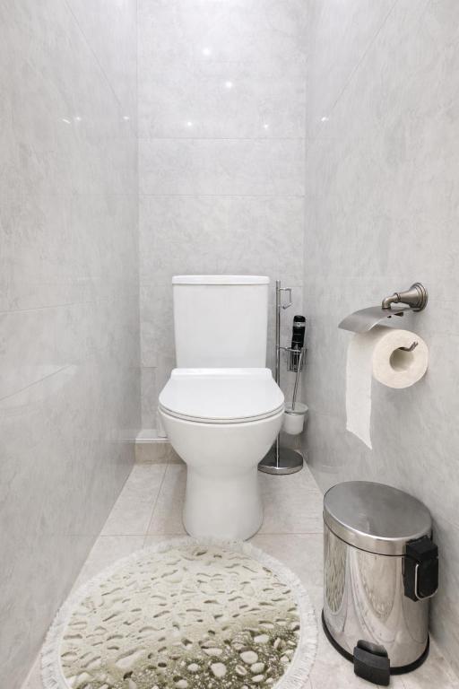 a white bathroom with a toilet and a rug at Boulevard 2BR Luxury Apartment in Tashkent