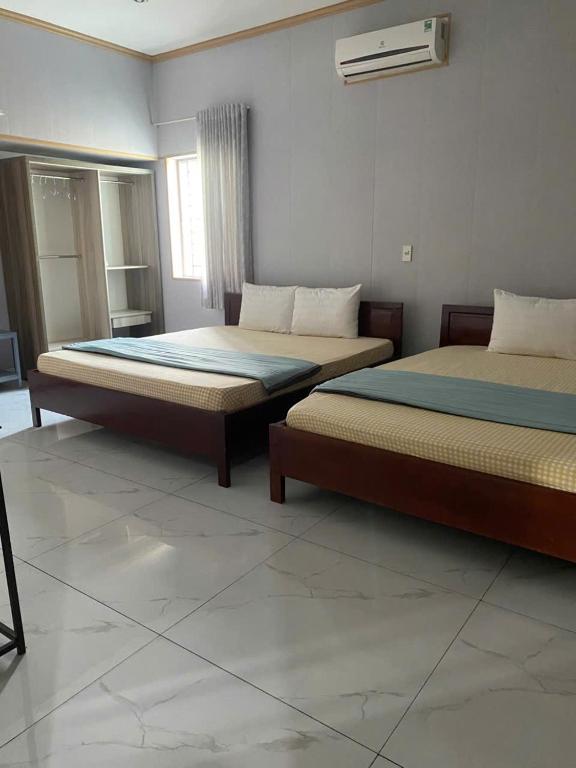 a bedroom with two beds and a window at NHÀ KHÁCH KEN in Cà Mau