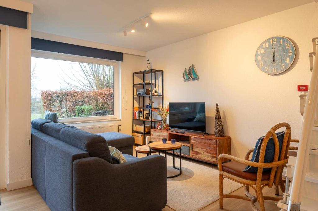 a living room with a blue couch and a tv at Fully equipped holiday home for 6 in Nieuwpoort
