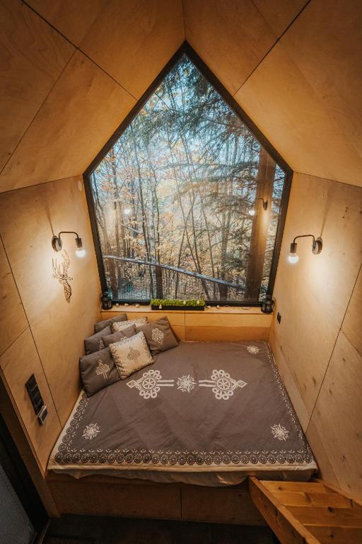 a small bed in a tiny house with a large window at Domek na drzewie Ceprowo in Szczyrk