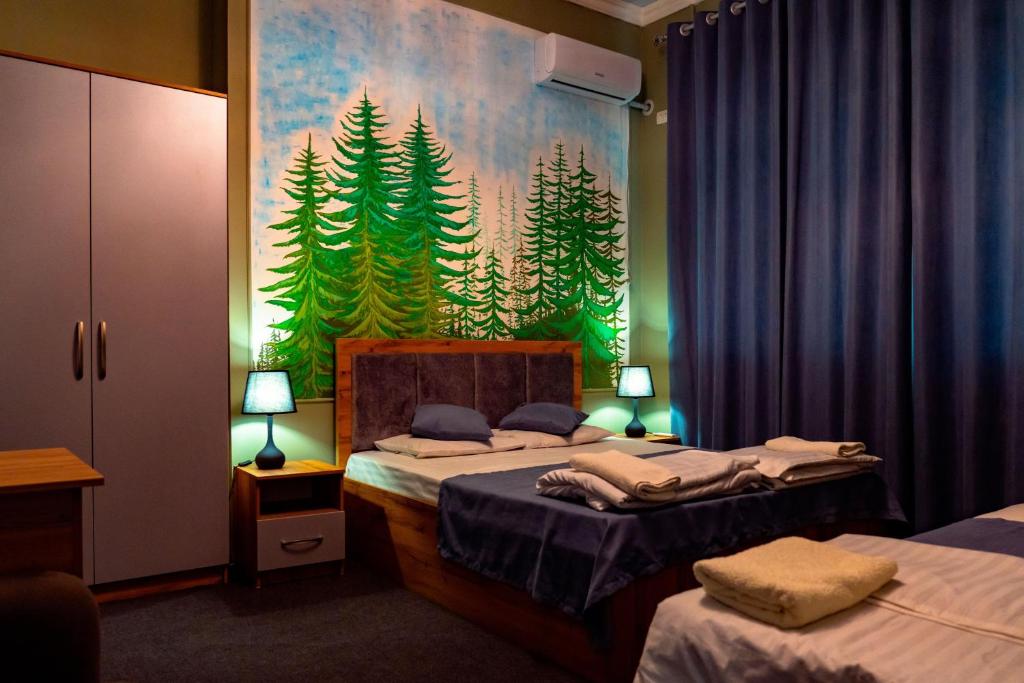 a bedroom with two beds and a painting of trees at Light Hostel by TripLE in Yakkasaray