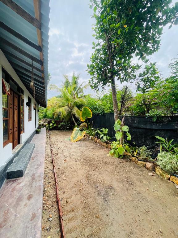 a dirt road next to a building with a tree at Hobbit in Midigama East