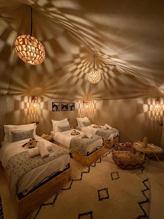 a bedroom with two beds and two lights at Peaceful Luxury Camp in Merzouga