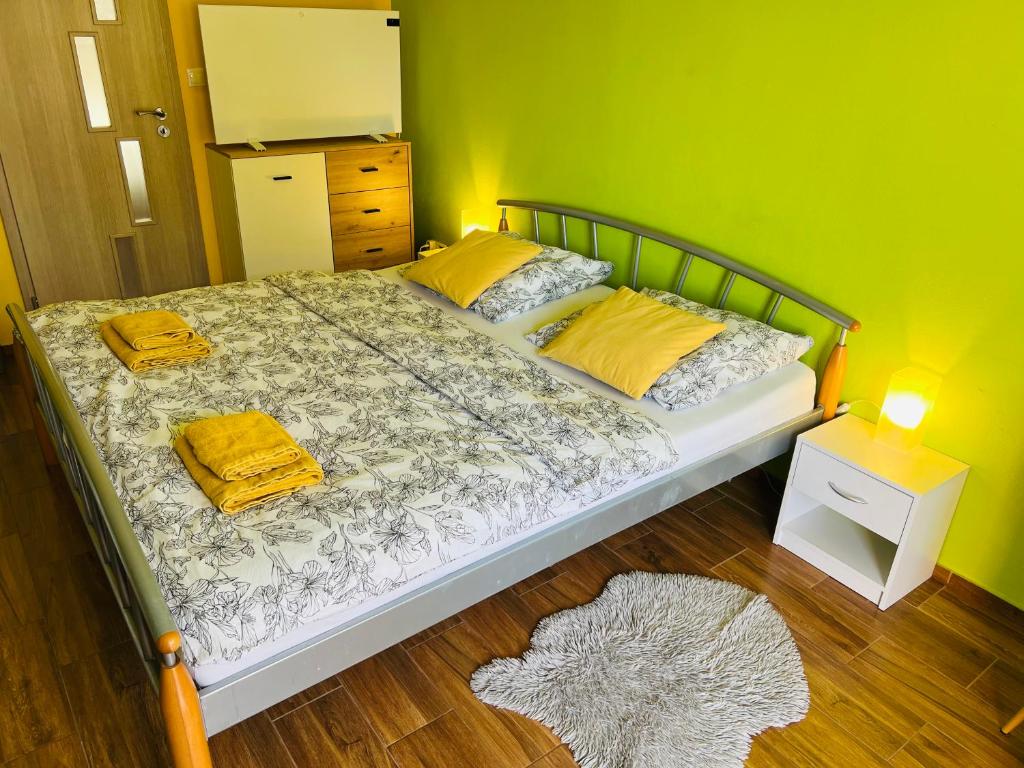 a bedroom with a bed with yellow pillows and a green wall at Apartmán Slivková in Trenčín