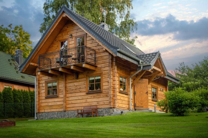 a log cabin with a balcony on a green lawn at Domek z bali in Jarnołtówek