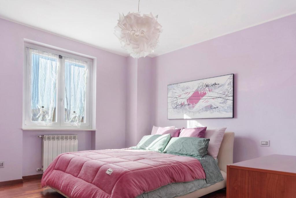 a bedroom with a pink bed and a chandelier at Villa Luna Al Lago in Biandronno
