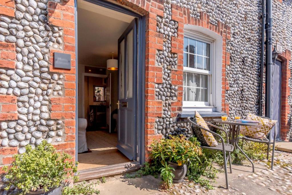 an open door of a brick building with a table at 1 Bed in Blakeney oc-674 in Blakeney