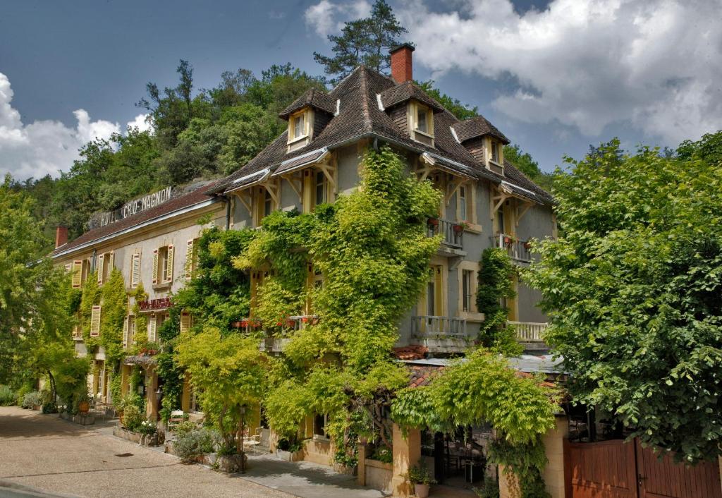 a building with ivy growing on the side of it at Hôtel Le Cro-Magnon in Les Eyzies-de-Tayac