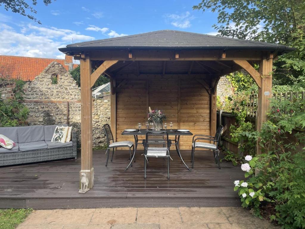 a wooden pavilion with a table and chairs on a deck at 2 Bed in Blakeney oc-1558 in Blakeney