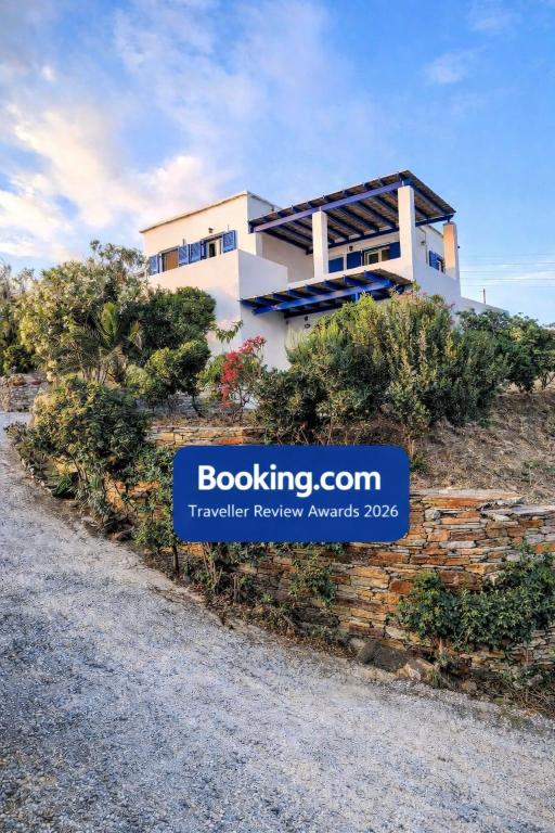 a house on a hill with a sign in front of it at Cycladic Horizon Island Villa By Hostandros in Batsi