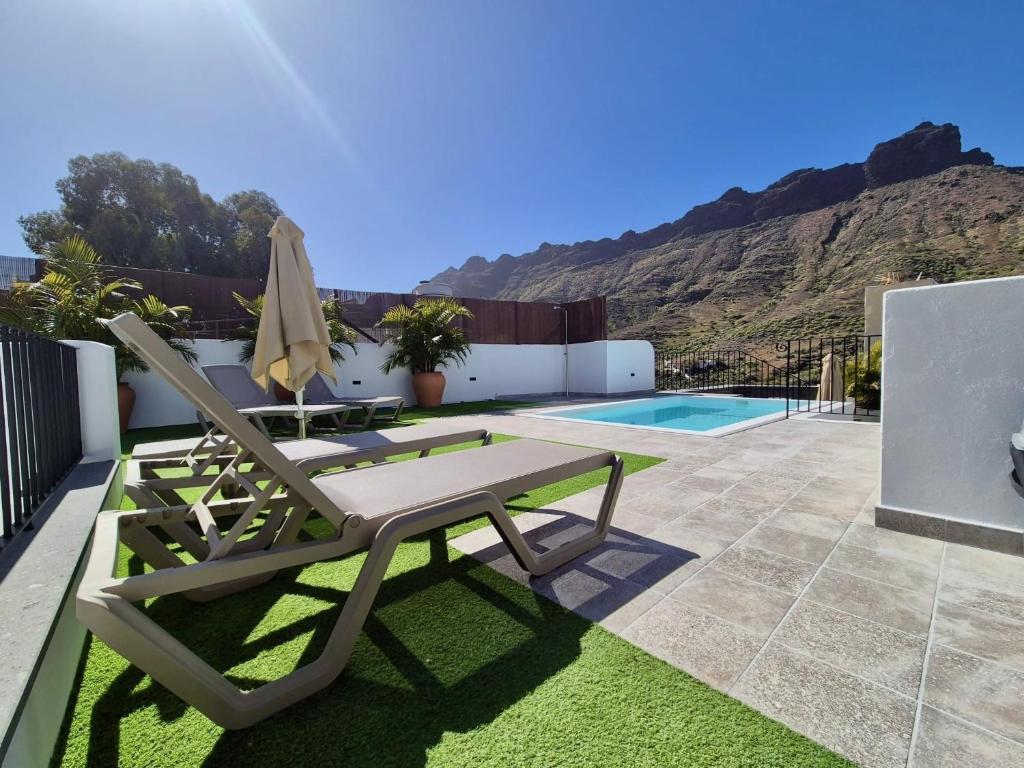 a patio with a table and chairs and a pool at Casa Federico & Manuela – Piscina Climatizada in Mogán