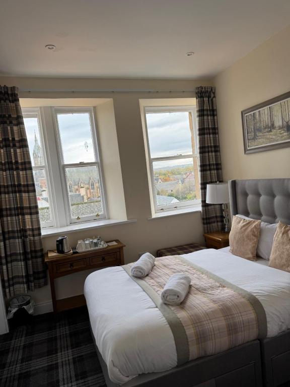 a bedroom with two beds and three windows at Royal Guest House in Dingwall