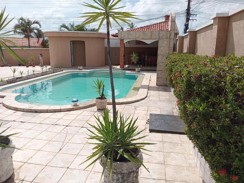 a swimming pool with a palm tree and a house at DOUBLE e RETIRO das PRINCESAS aluguel de quartos in Salinópolis