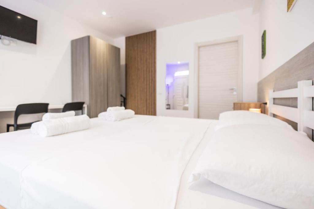 two white beds in a white bedroom with chairs at MAGGIORE Affittacamere in Ravenna